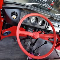 Werkstattinnenraum mit rotem VW-Käfer-Cockpit in Restaurierung